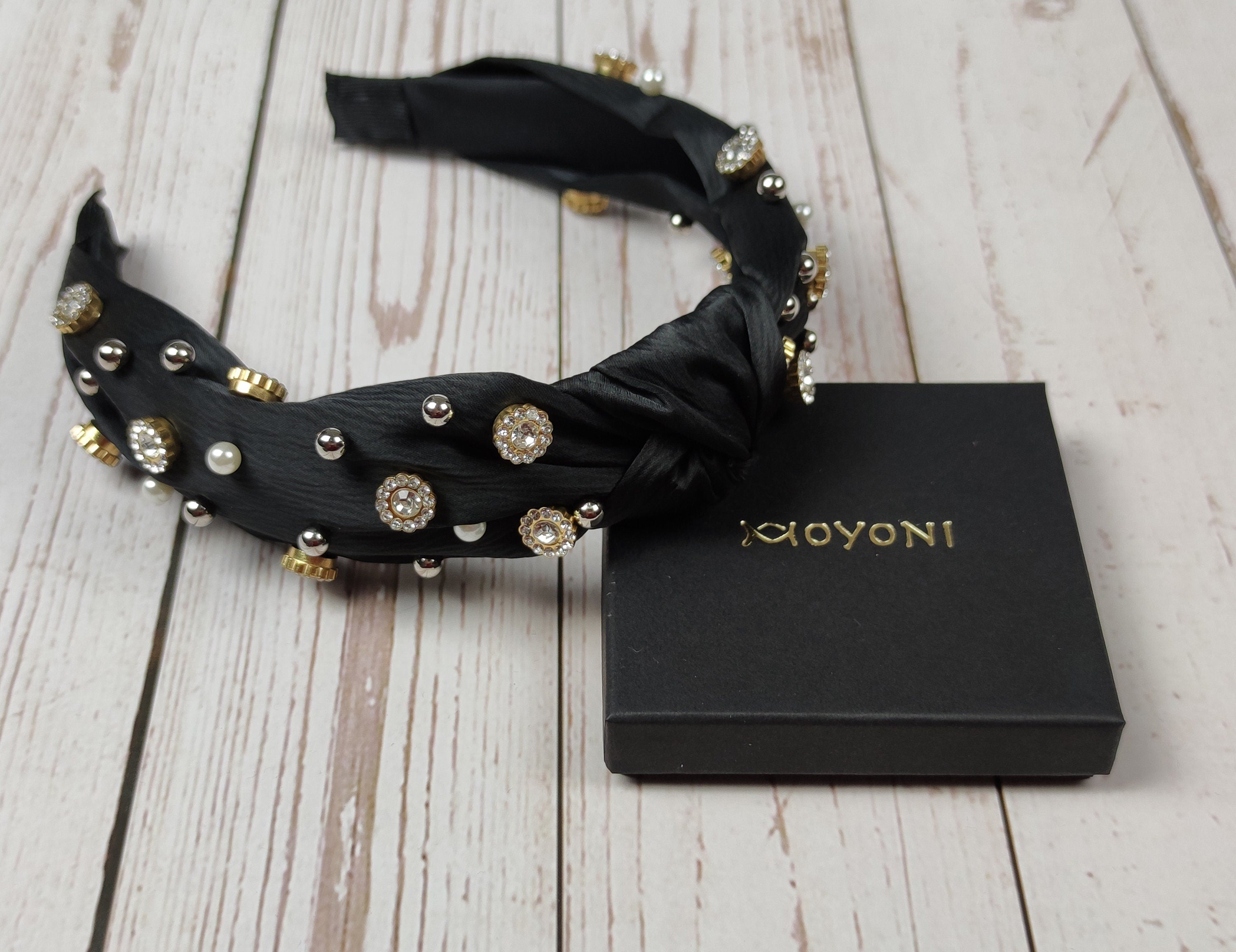 Make a bold statement with this one-of-a-kind black satin headband, featuring an eye-catching gemstone and pearl design.