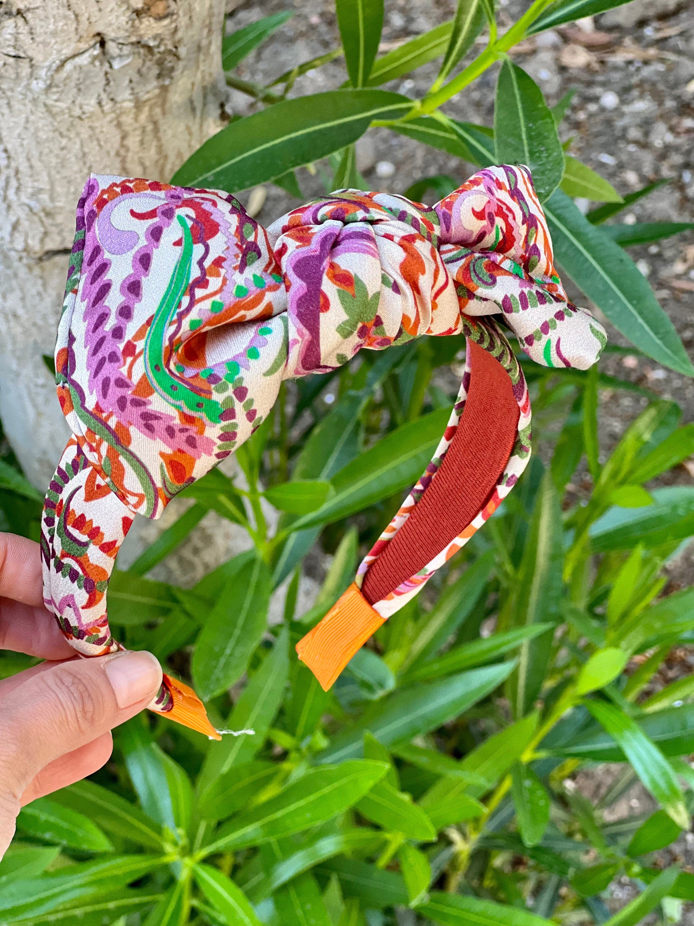 Keep your hair in place in style with this beige orange green hair tie headband