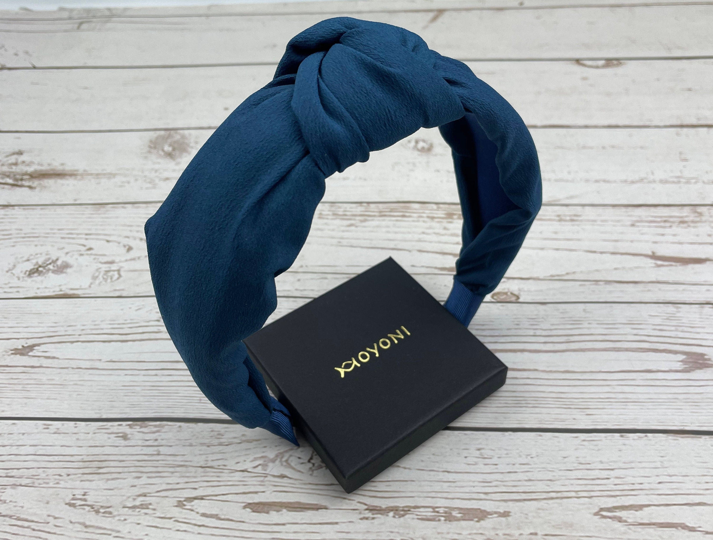 Add a touch of elegance to your look with this knotted headband made from soft, padded viscose crepe material in a rich dark blue color.