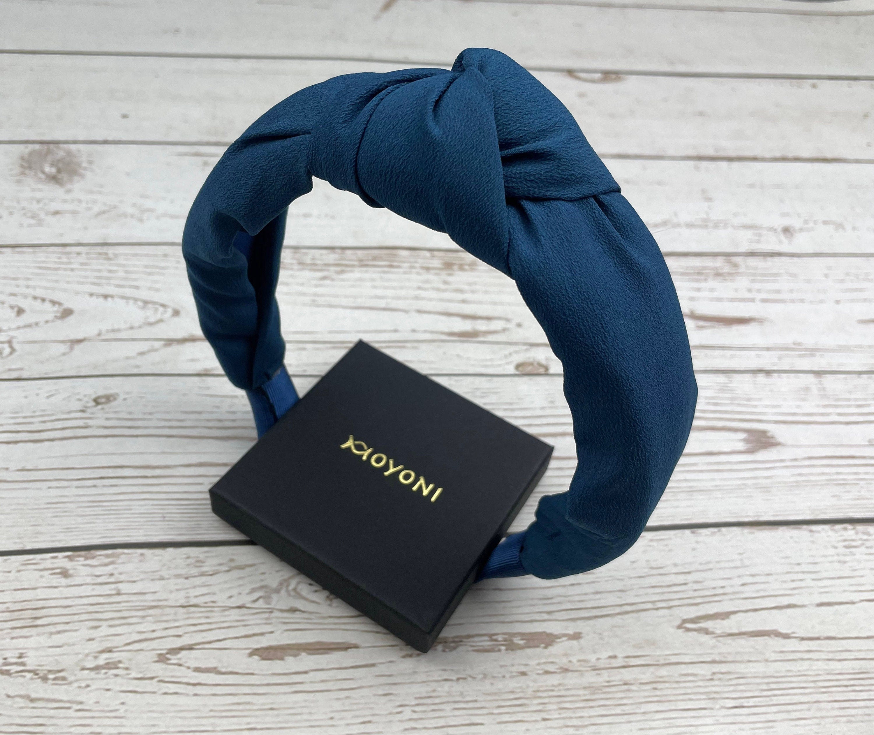 Get the perfect fit and a touch of sophistication with this classic headband, designed with a knotted twist in a dark shade.