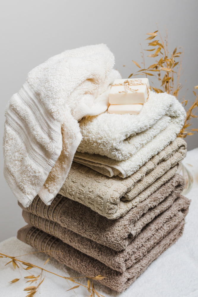 Collection of soft, colorful bath towels neatly stacked on a shelf, showcasing various textures and patterns.