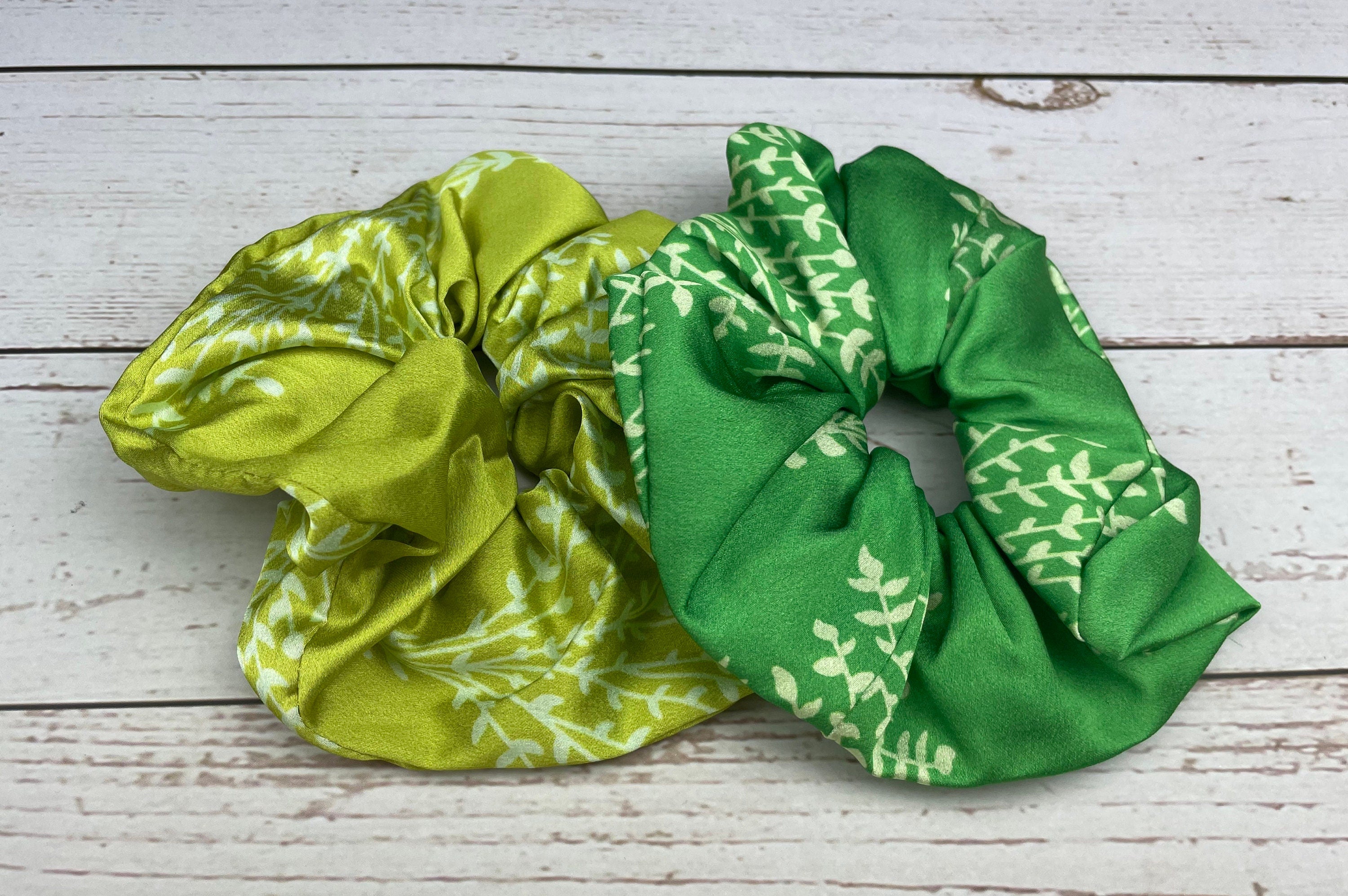 Upgrade your hair accessories with this handmade scrunchie, featuring a charming satin bow and a fun leaf pattern in a rainbow of colors.