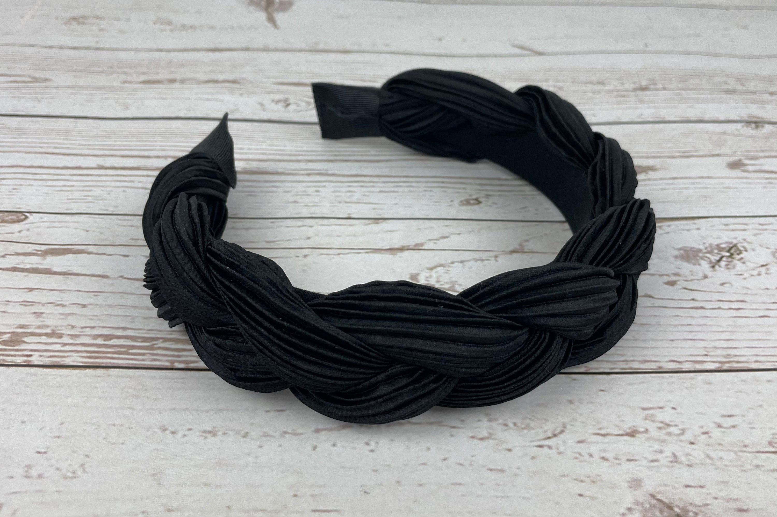 A stylish twisted women&#39;s headband in black, featuring a unique design that adds a touch of sophistication to any outfit.