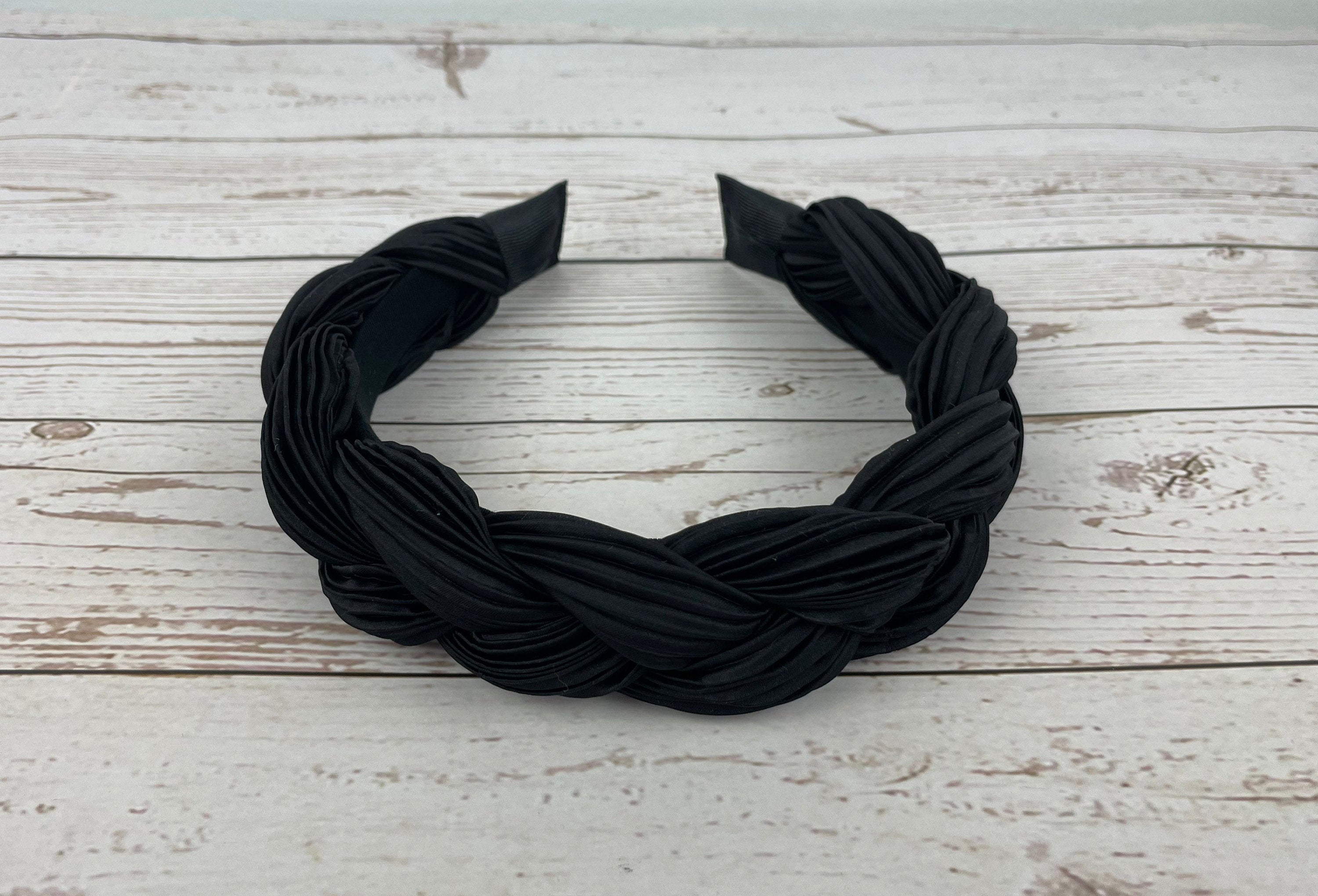 A close-up shot of a black padded satin headband, showcasing its smooth texture and elegant black color.