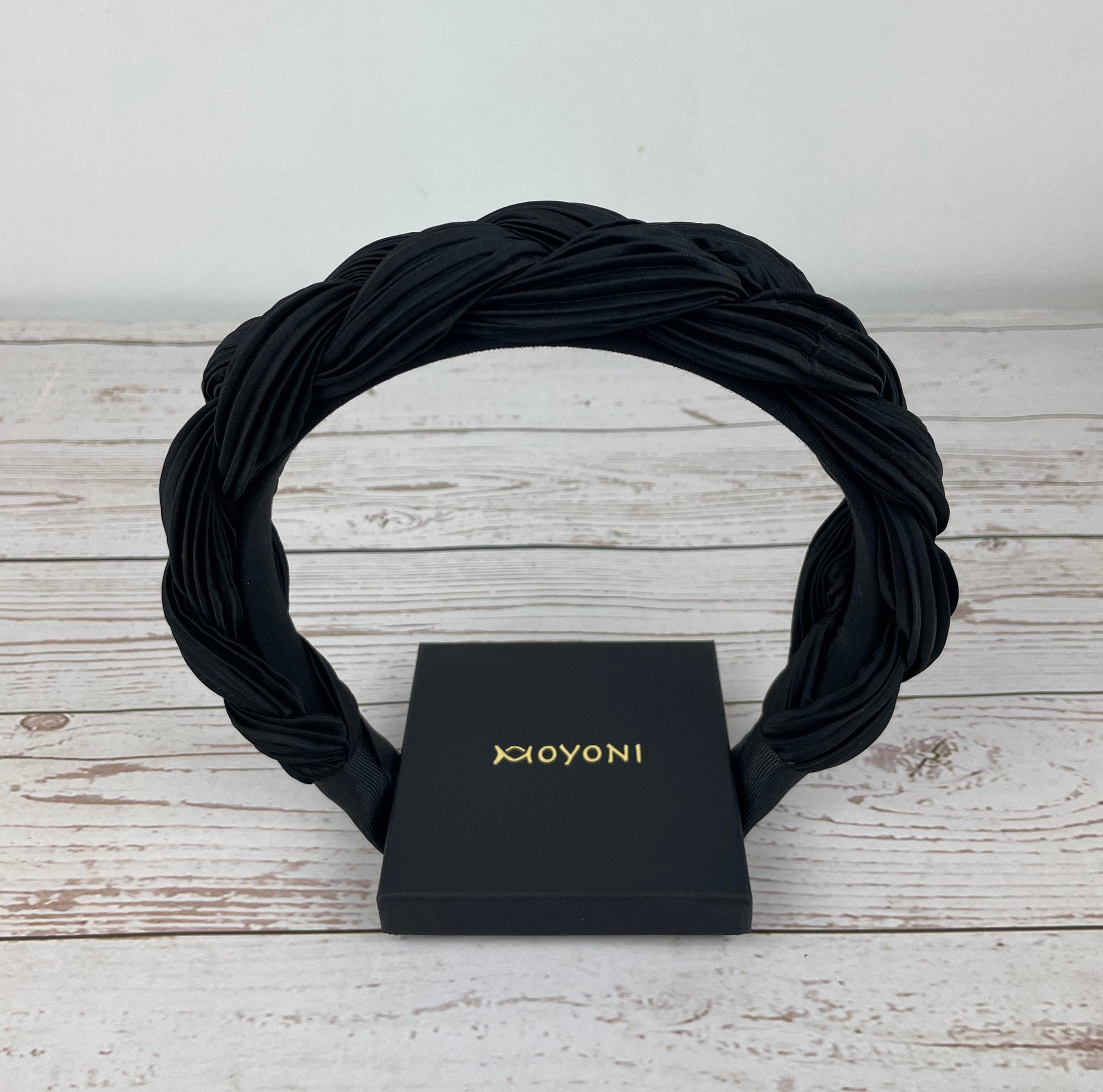 A dark-colored braided turban hairband, perfect for adding a boho-chic vibe to your hairstyle with its black braided pattern.