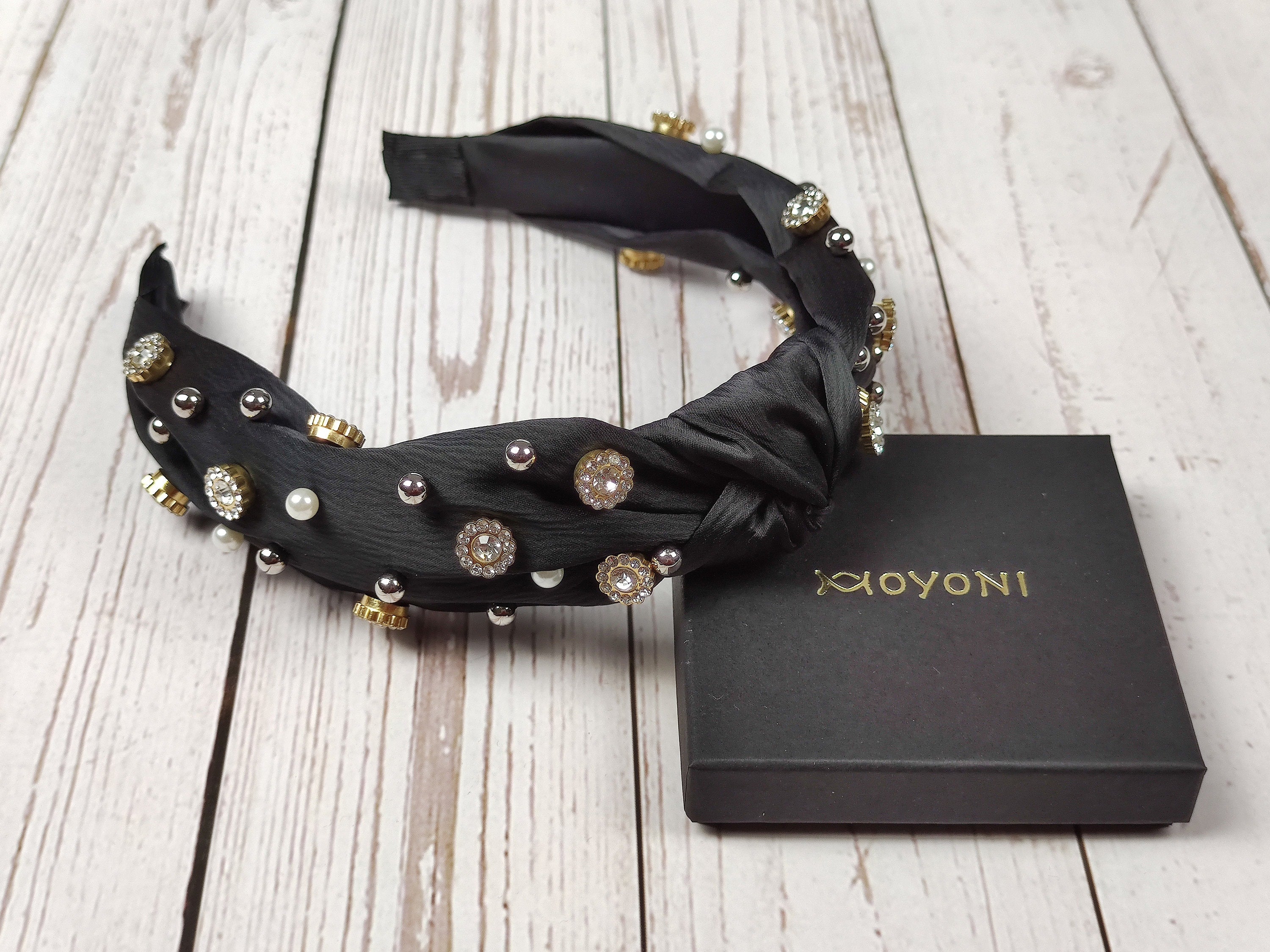 Make a statement with this stylish black satin knotted headband, embellished with sparkling gemstones and pearls.
