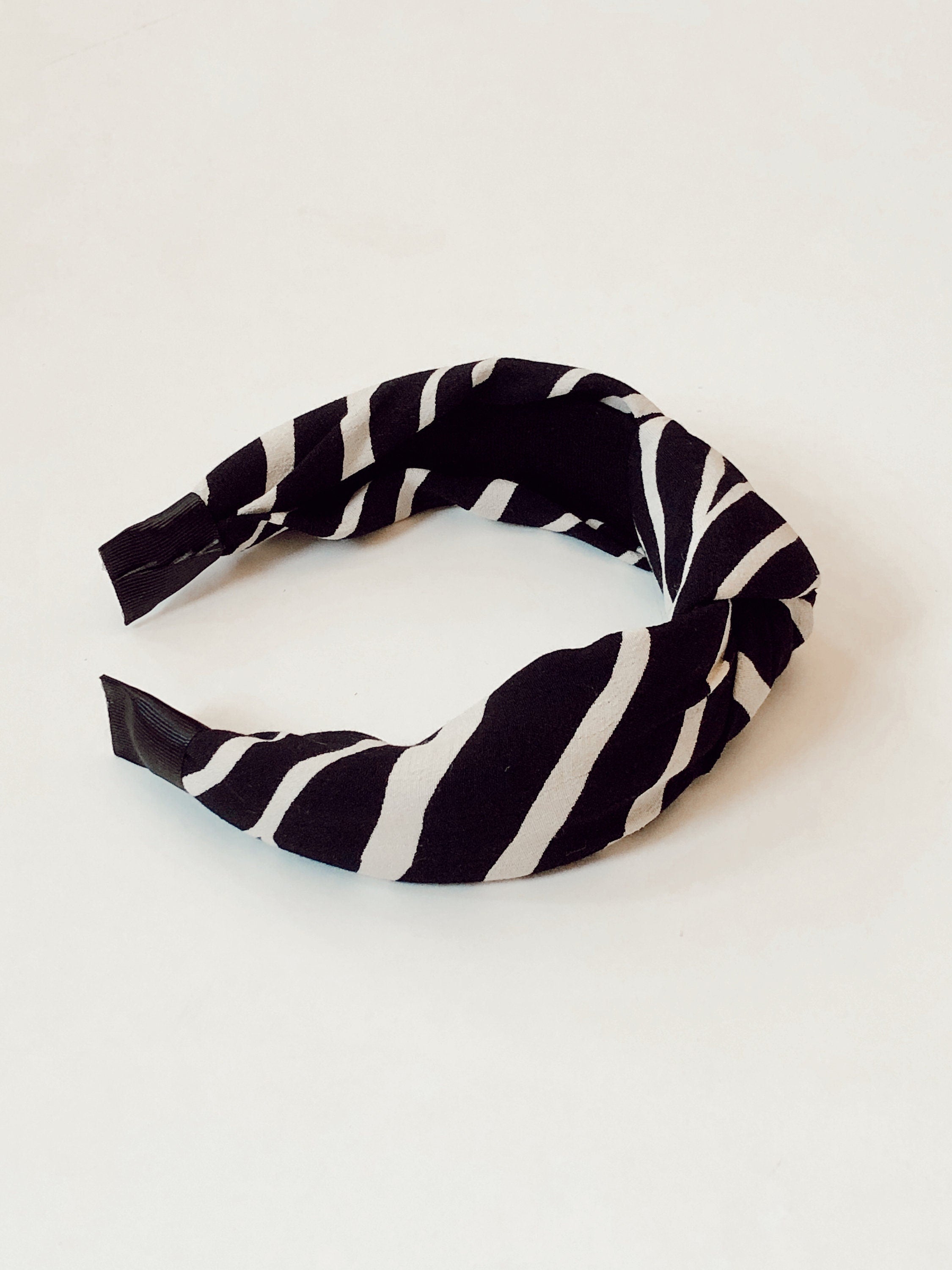 Make a statement with this fashionable knotted headband, featuring a zebra pattern and a classic off-white and black color scheme.