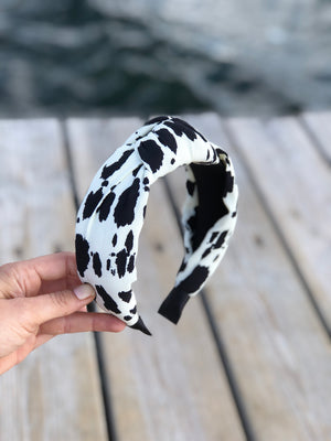 Add a touch of edgy sophistication to any look with this white leopard headband, featuring black spots and a stylish bow.