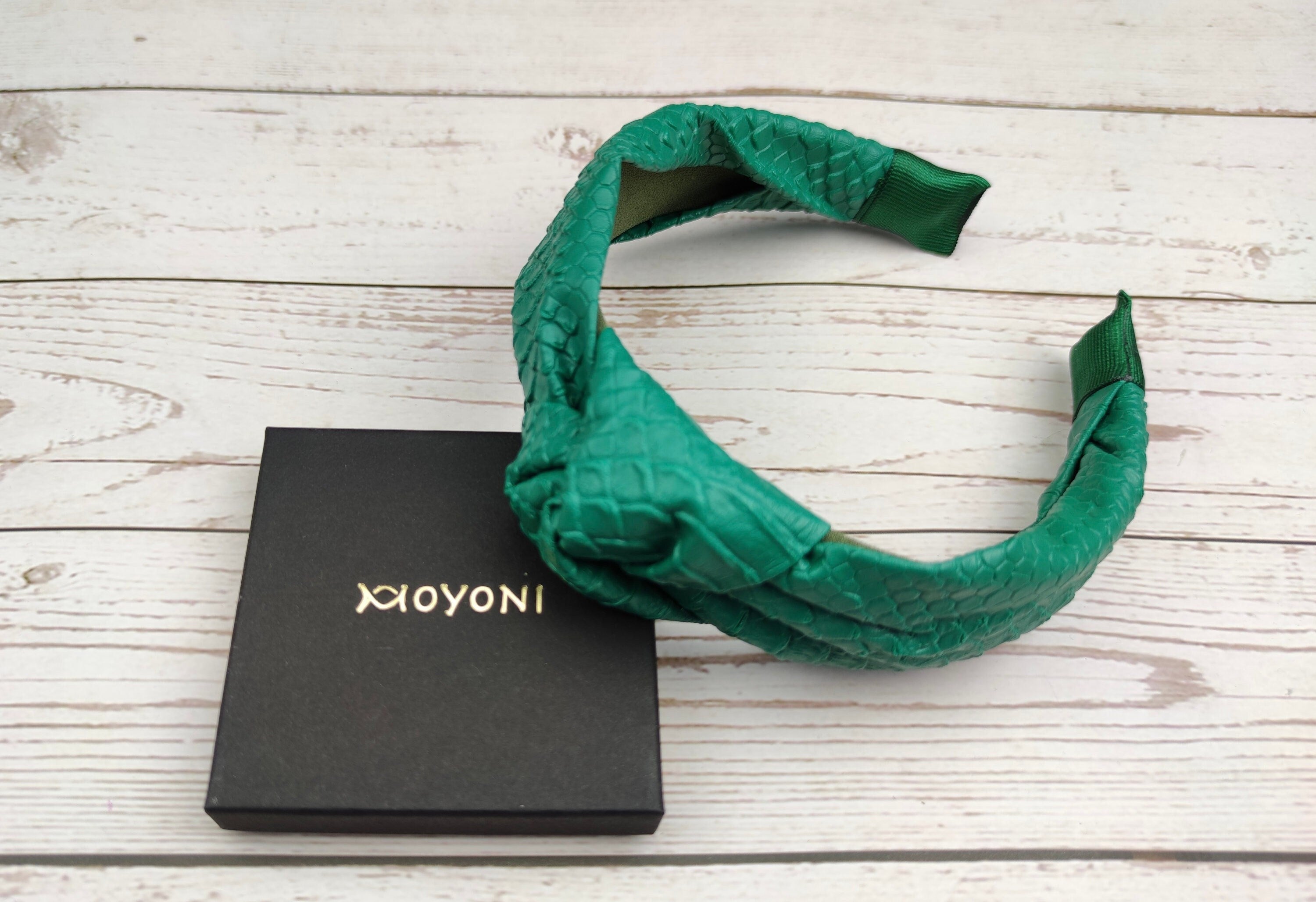 Elevate your look with this green faux leather twist headband.