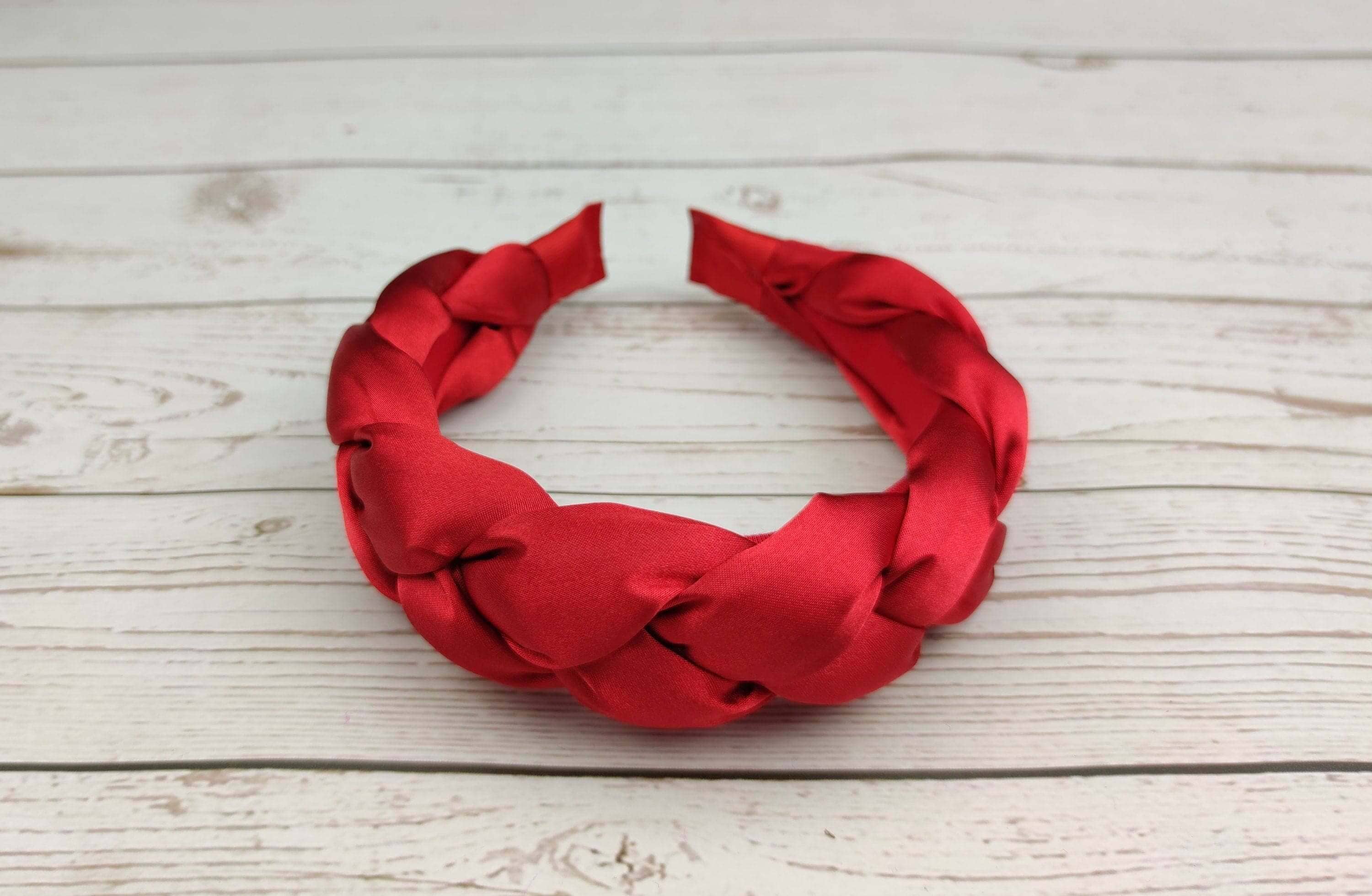 Stay stylish and comfortable with this padded red satin headband, featuring a braided design.