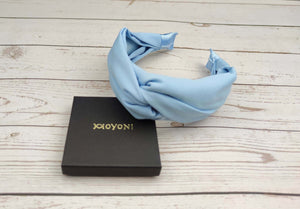 A close-up image of a baby blue twist knot headband made of soft viscose crepe material. Perfect for adding a touch of elegance to your everyday look.