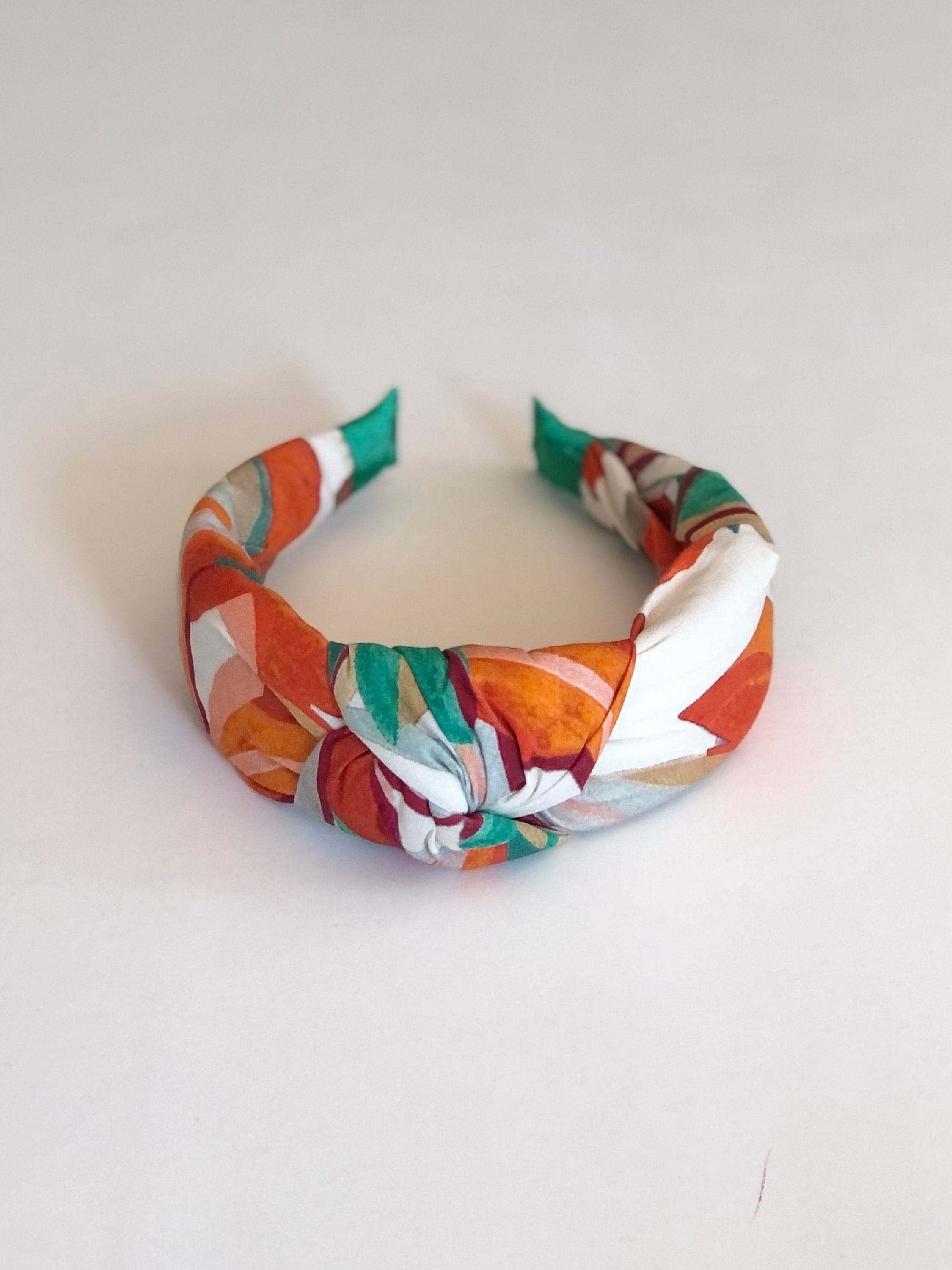 The perfect accessory for any outfit - a versatile knotted headband in a trendy cream, orange, and green color combination.