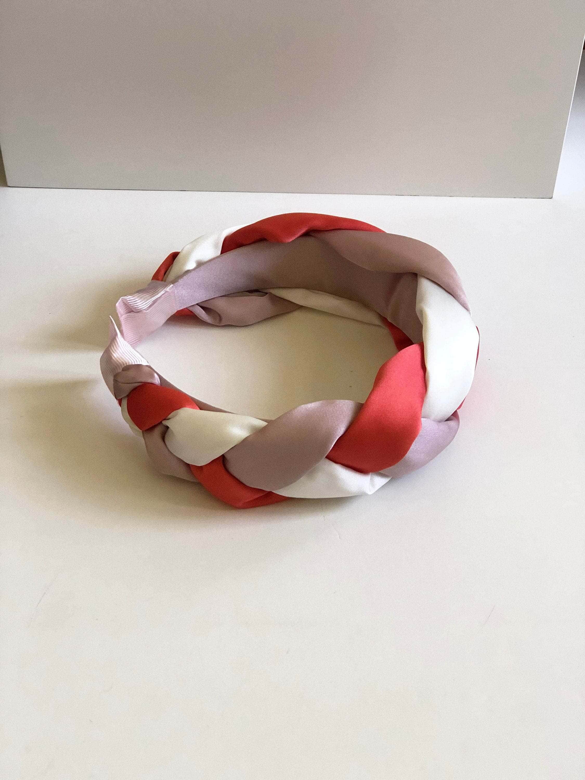Make a fashion statement with this beautiful lilac, white, and light red padded satin headband, featuring a twisted design.