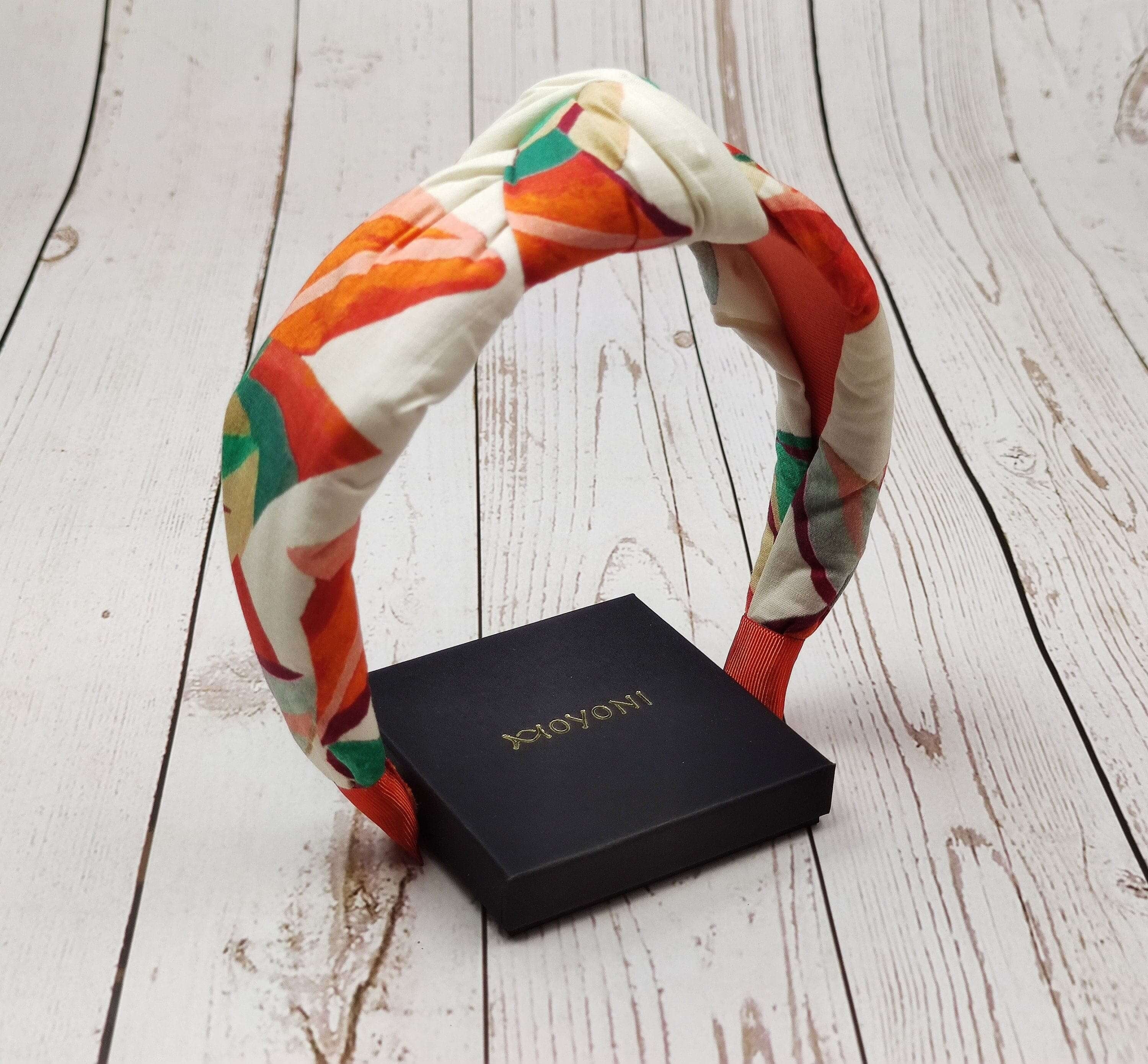 Add a pop of color to her hair accessory collection with this trendy knotted headband in cream, orange, and green.
