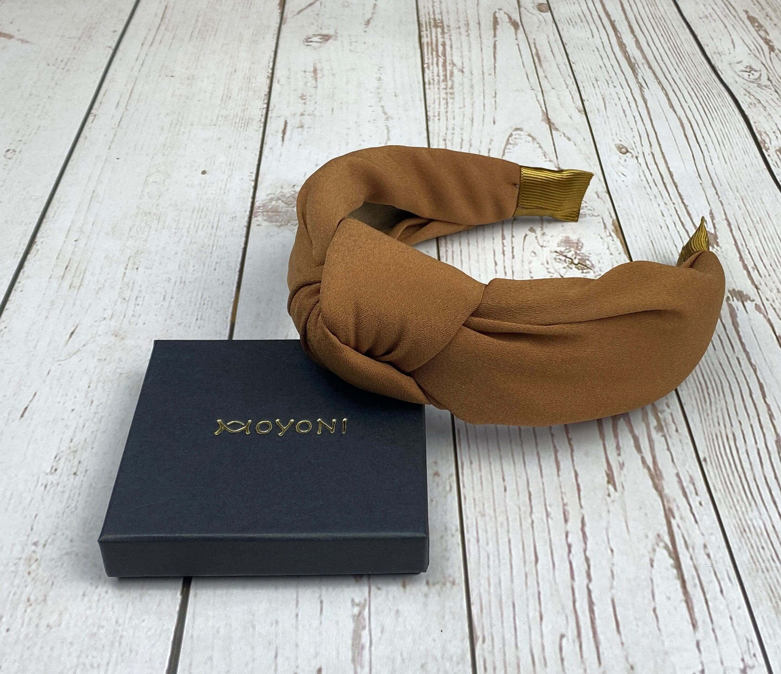 Stay stylish and comfortable with this brown padded crepe headband, featuring a knotted design.