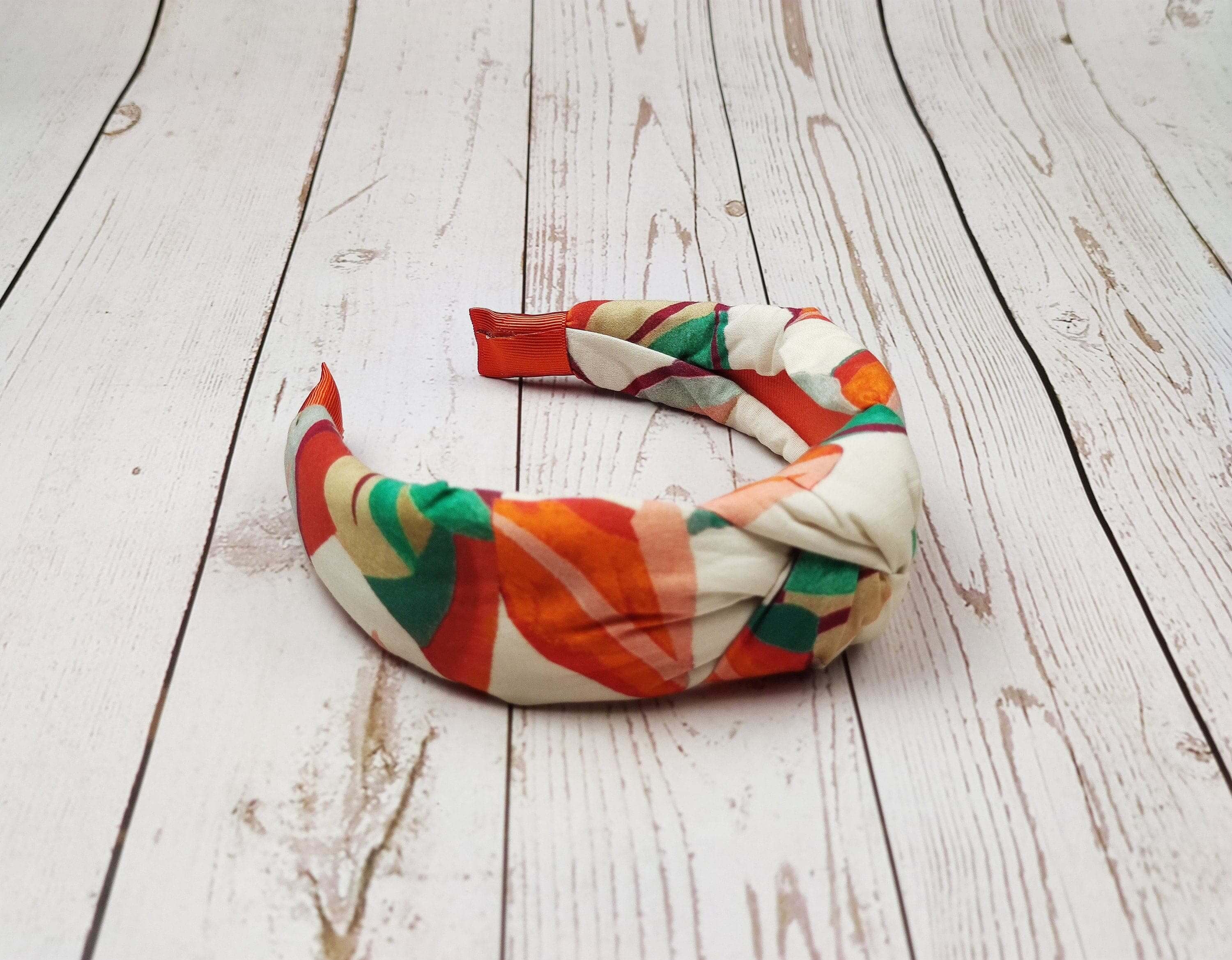 Upgrade her hair game with this must-have knotted headband in a bold cream, orange, and green color scheme.