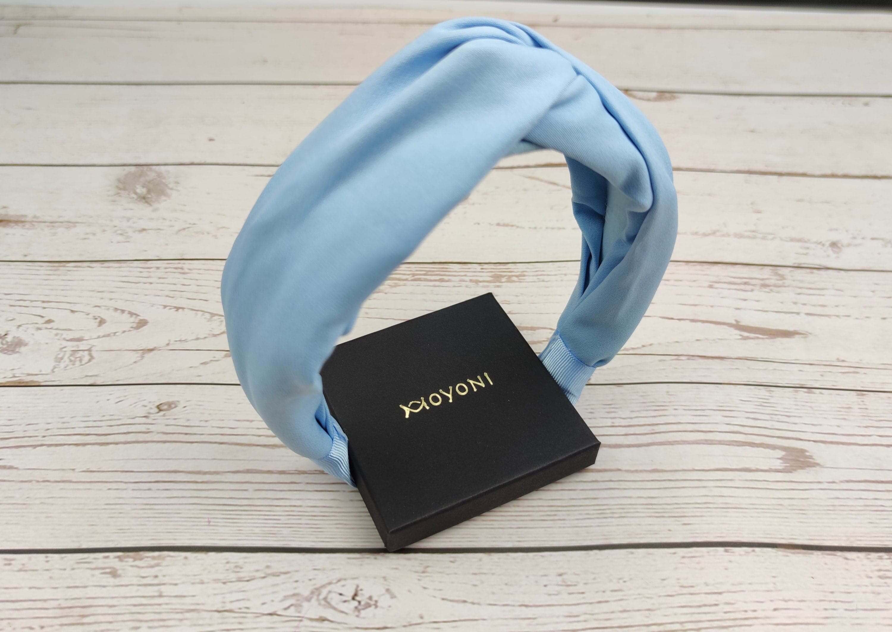 An image of a wearing a light blue headband. The soft and stretchy material makes it comfortable for little ones to wear while adding a cute accessory to their outfit.