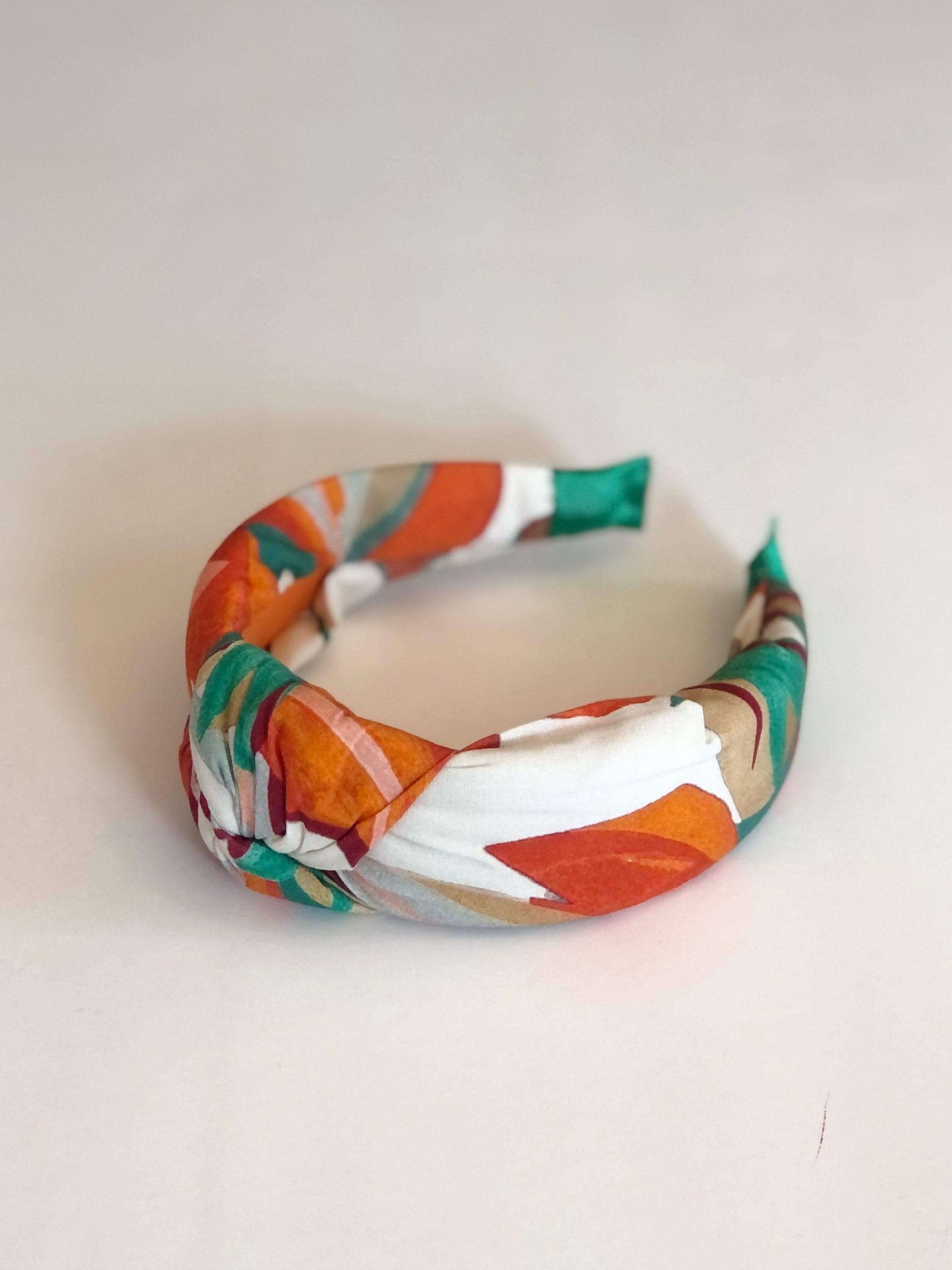 Make a statement with this eye-catching knotted headband, featuring a fun leaf pattern and bold color scheme.