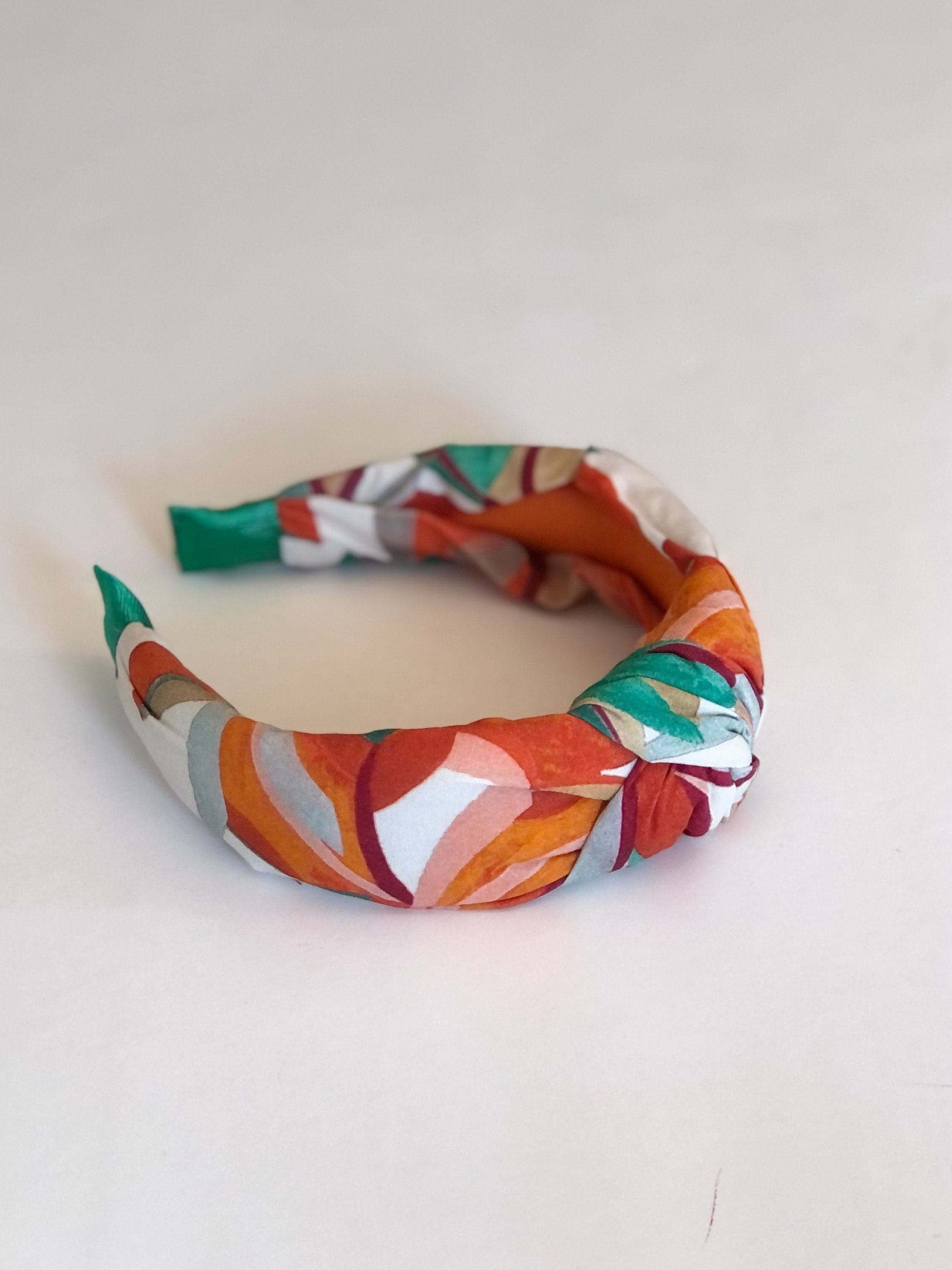 Treat her to a stylish and comfortable hair accessory with this knotted headband in a unique cream, orange, and green colorway.