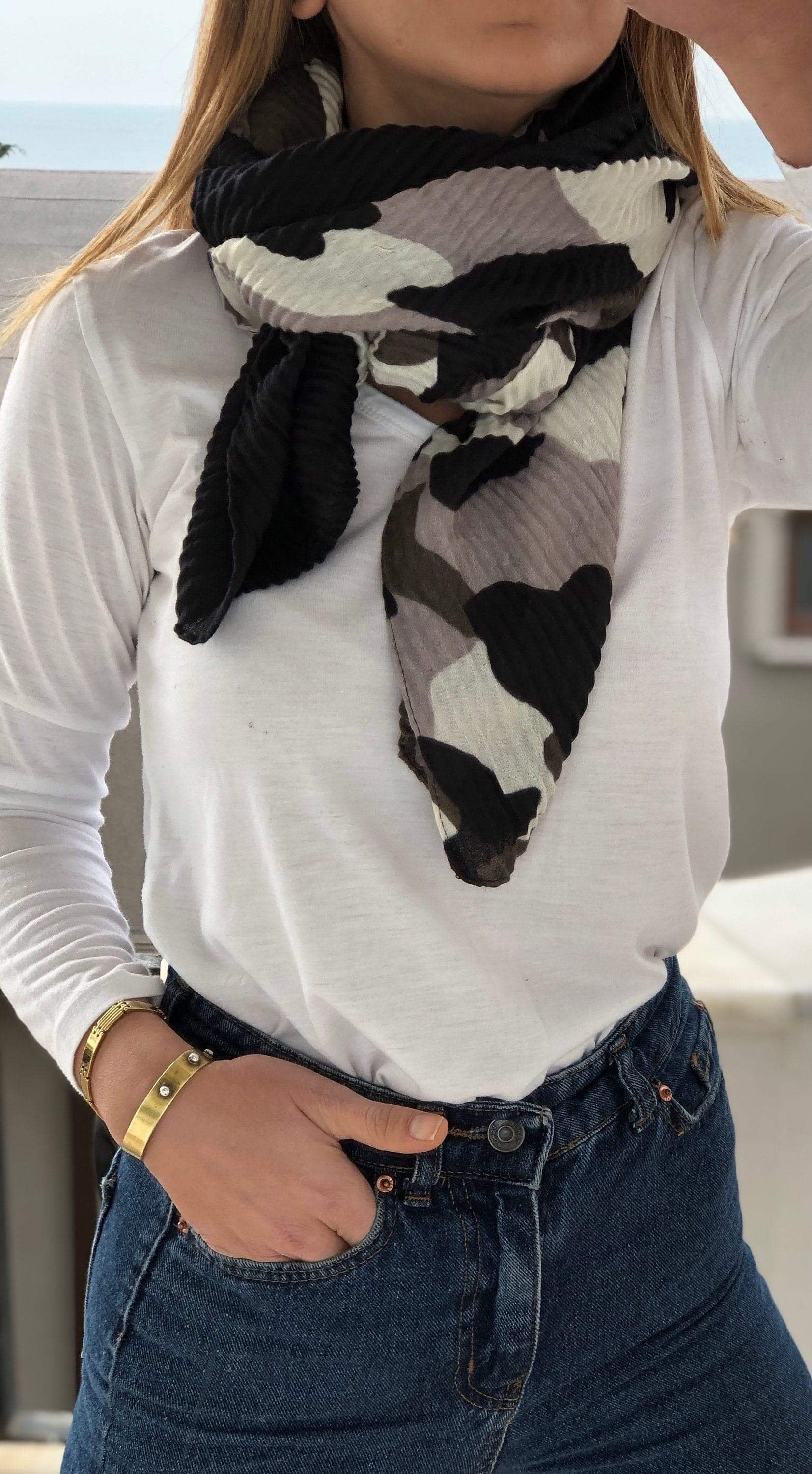 Stay cozy and on-trend with this dark-colored camouflage patterned scarf.