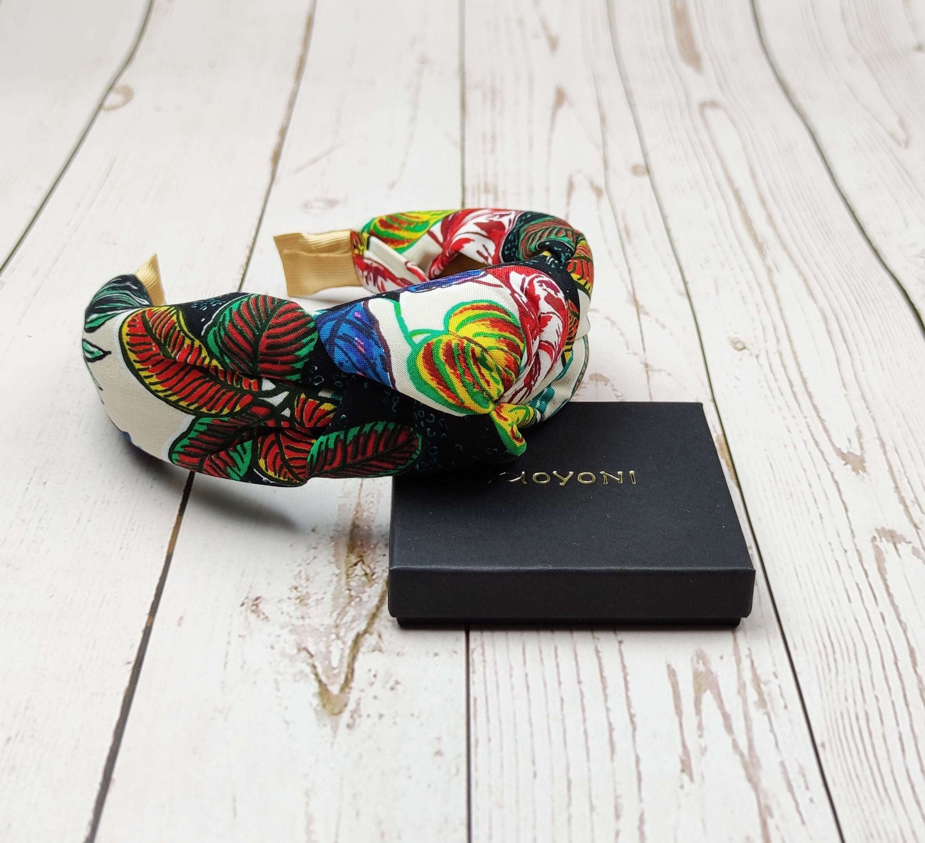 Stay stylish and comfortable with this knotted headband in a vibrant mix of dark blue, yellow, green, and red.